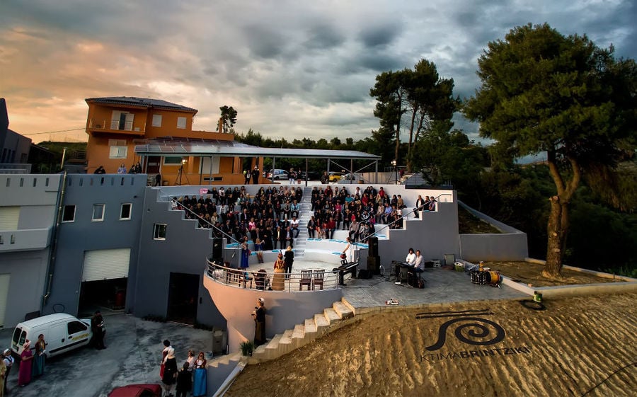 tourists sitting on stone amphitheater, listening to concert outside Ktima Brintziki winery